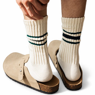 Hand pulling up a cream ribbed crew sock with green and black stripes